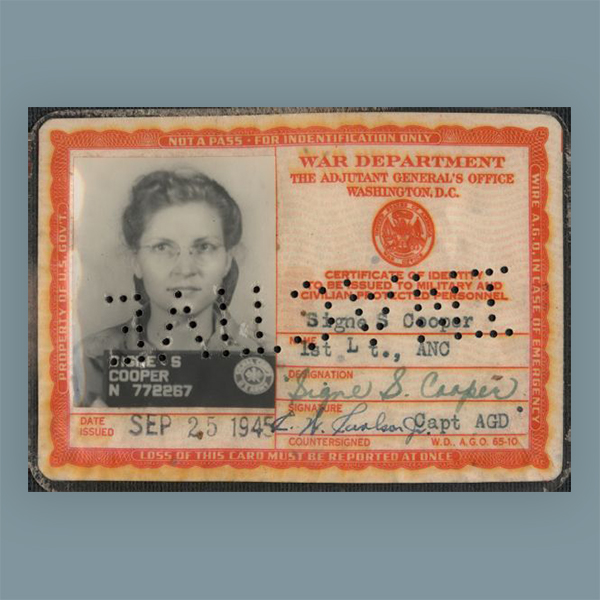 The identification card of Signe S. (Skott) Cooper, 1st Lt., ANC. (First Lieutenan, Army Nurse Corps.) The card was issued SEP 25 1945. Her photograph is on the left, name and signatures on the right. When the card is reversed, the punched holes across the ID spell 'INACTIVE.' 